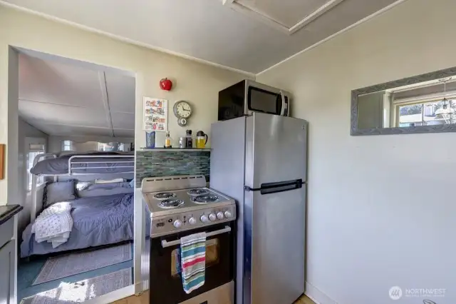 Kitchen with all stainless appliances. Main bedroom and extra sleeping room it through the doorway.