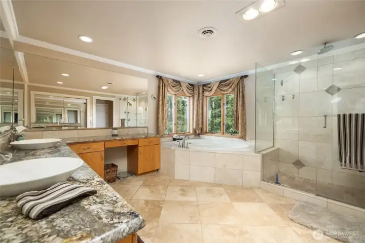 Primary bathroom with double sinks, large jetted tub and large walk in shower with travertine flooring.