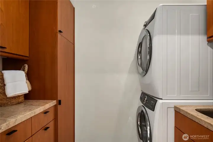 Just off the huge walk-in closet is this full size laundry room with a sink (to the right) and more built-ins with granite counters.