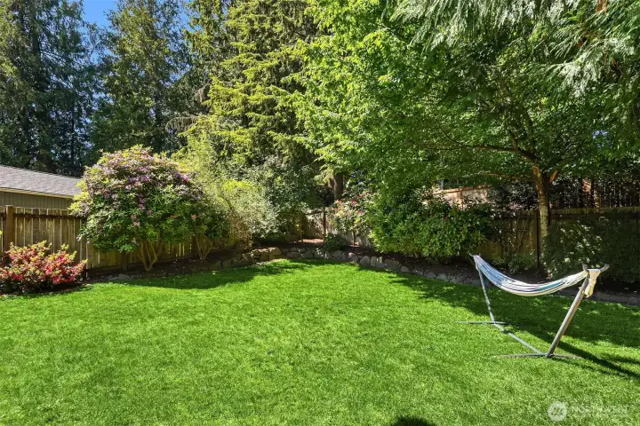 Yard is filled with mature trees and bushes