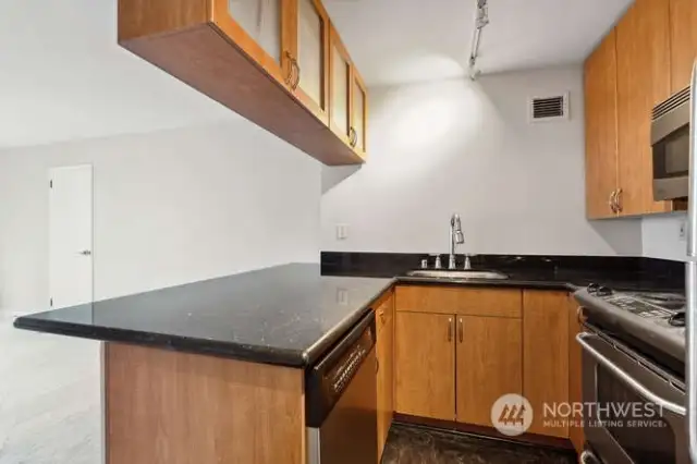 Efficient kitchen with granite counters, cherry cabinets, and stainless appliances.