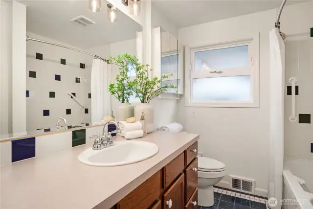 The main floor bathroom (one of two) features tiled floors and tub surround as well as fantastic storage.