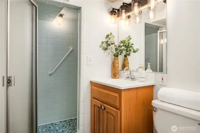 The lower bathroom features a walk-in tiled shower and a wood vanity.