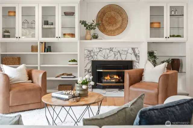 Glass door cabinets with open shelving and a gas insert fireplace with marble surround.