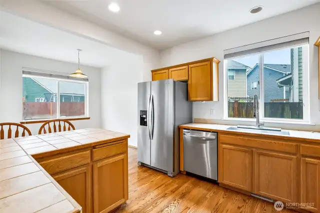 Kitchen with stainless steel appliances, tile countertops and hardwood floors.