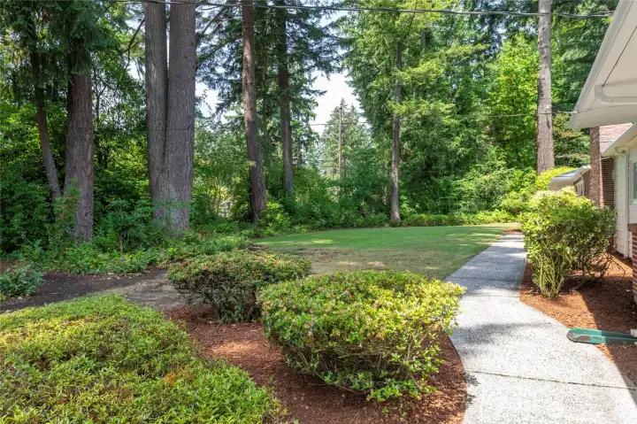 View of the side of the house with mature landscaping and walkway that leads to another entrance into the home.