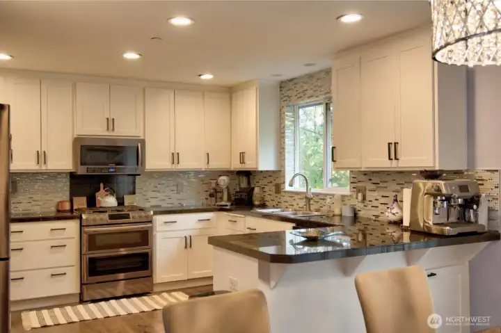 Kitchen open to dining with granite counter top and custom backsplash.