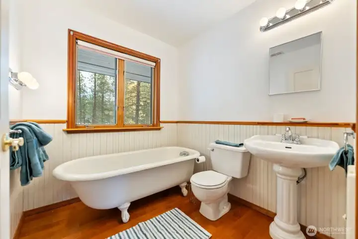 Main level Bathroom Farmhouse vintage with genuine clawfoot tub & pedestal sink. Wood panel  with wood trim. Cherry-wood floor. Bright, fresh and clean.