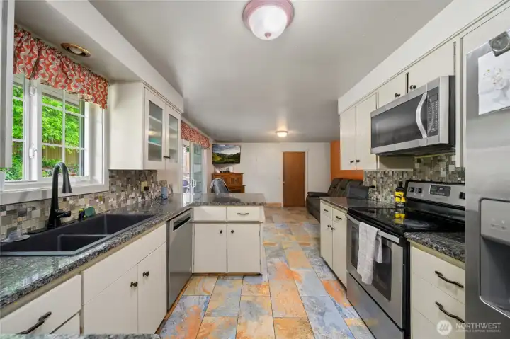 Granite countertops, tiled floor, stainless steel appliances, that flows to the den/television room.