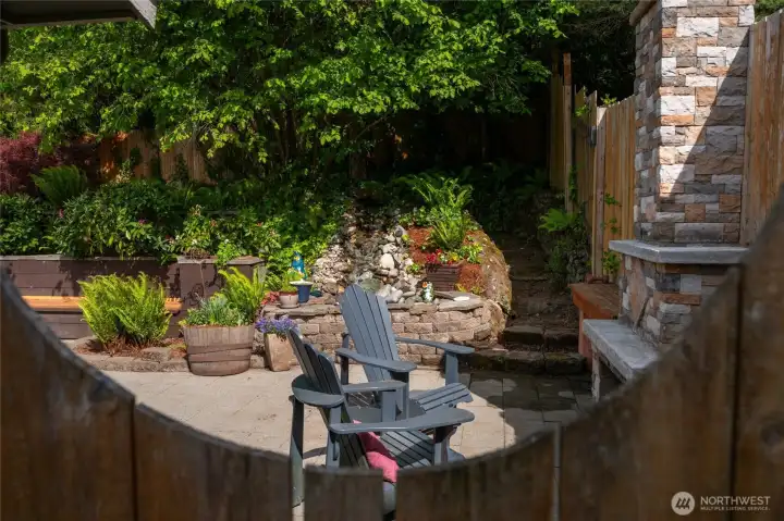 An outdoor stone wood burning fireplace and waterfall.