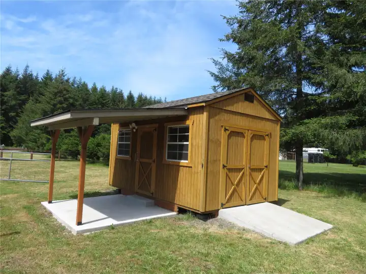 Outbuilding with ramp for lawn equipment