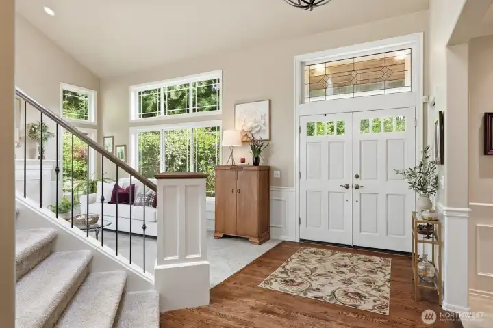 A graceful open staircase featuring iron railings. Large windows frame views of the manicured grounds while allowing abundant natural light to pour in.