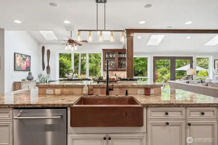 At the center of the space, a large island serves as a natural gathering place and features a striking hammered copper farmhouse sink, breakfast bar seating, and generous workspace.