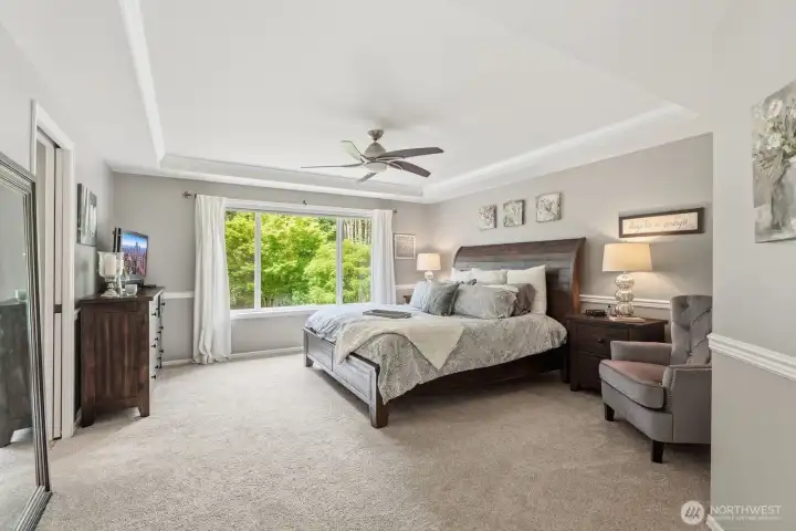Upstairs, the home continues to impress with four bedrooms, including a luxurious primary suite designed as a private retreat. The bedroom features chair rail molding, a ceiling fan, and expansive windows that capture breathtaking backyard views.
