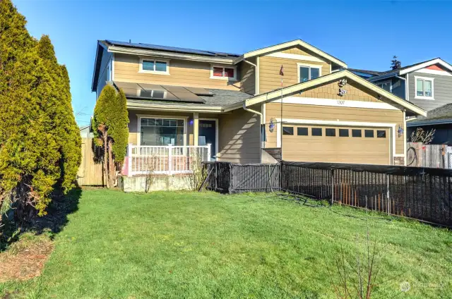 Cozy porch overlooks fully fenced front yard.