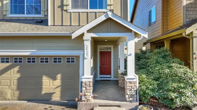 A warm color palette complemented by a charming red front door adds warmth and character to the home's inviting curb appeal.