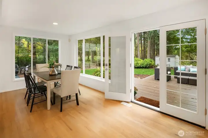 The expansive casual dining area features oversized windows that flood the space with natural light and a seamless transition to the outdoor deck—ideal for effortless indoor-outdoor entertaining.