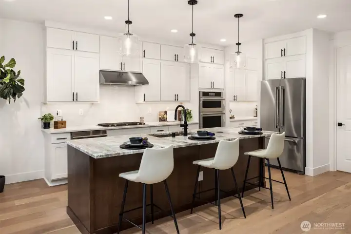 Gourmet kitchen with upgraded cabinetry, top of the line JennAir Appliances, beverage fridge and gas cooking Photos are for illustrative purposes only