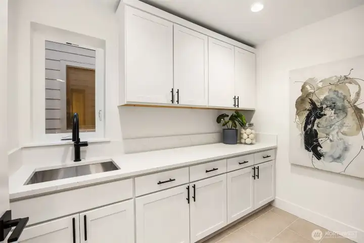 Abundance of cabinets and sink in the laundry room   Photos are for illustrative purposes only