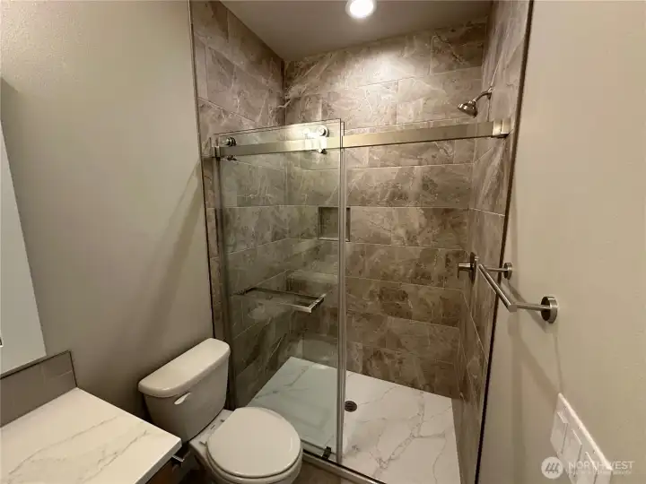 FOR ILLUSTRATION PURPOSES Main floor guest walk in shower with quartz floor and tile surround.