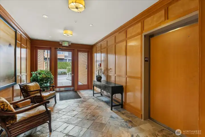 Wood paneled lobby with slate tile flooring to access elevator . . .