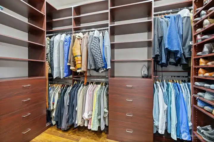 This impeccably organized walk-in closet features custom shelving and drawers, ensuring every item has its place, making it easy to maintain an uncluttered and serene environment.