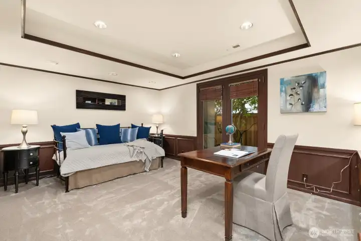 The lower-level office, adorned with rich mahogony built-ins, offers a versatile space that can function as a private study or guest quarters, with a dedicated full bath and direct access to a private outdoor patio.