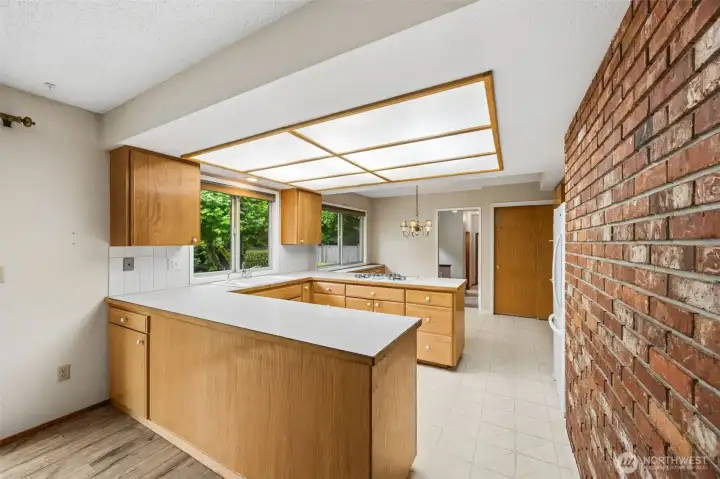Smart U-shaped kitchen provides lots of counter space with storage below. Beautiful brick carries through the home.