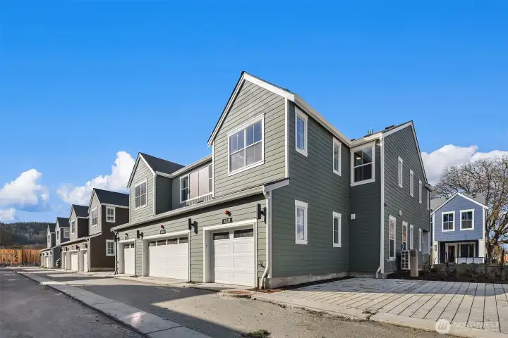 Rear view of home with one car garage and guest parking next to home. Similar home shown.