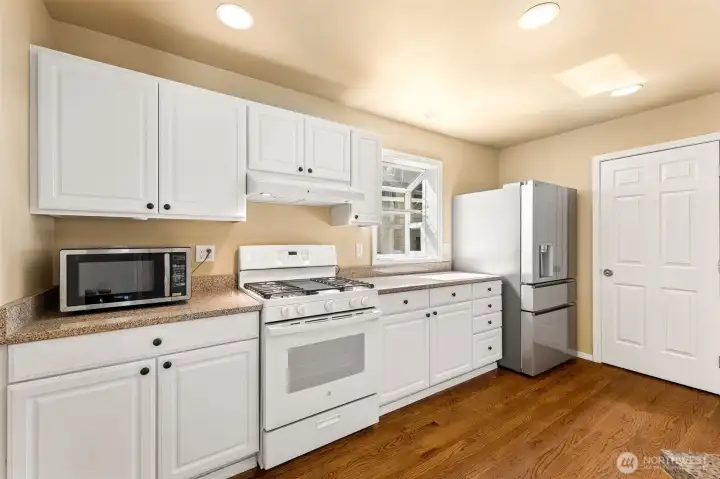 Gas range and a brand new fridge. Pantry adjacent to the fridge.