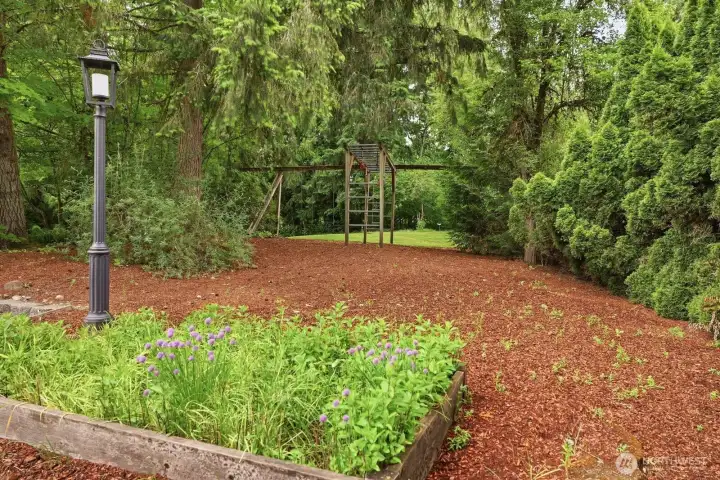 The front side yard with raised garden bed and play structure. The front side yard with raised garden bed and play structure.