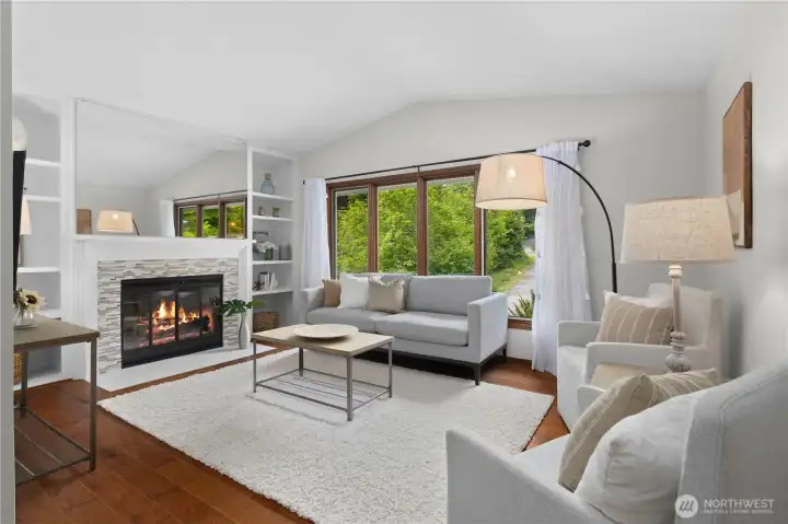 Living room with a vaulted ceiling and cozy wood-burning fireplace.