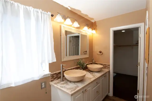 Primary Bath with Double Vanity, Stone Flooring, Marble Countertops w/Stone Sinks, and a Large Walk-in Closet.