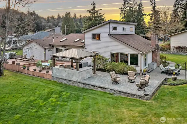 Back of the home, facing the river, with multiple decks, paver patios and covered outdoor kitchen!