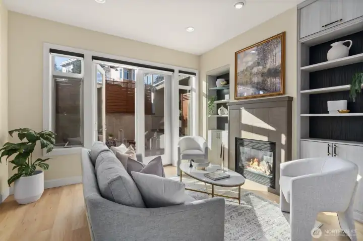 Living room is drenched with sunlight, boasting high ceilings, built in bookshelves, topped off with a cozy gas fireplace.