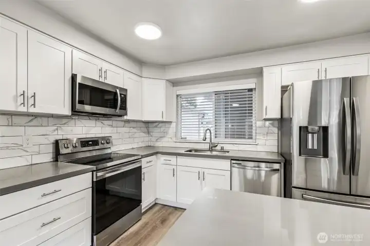 The updated kitchen boasts quartz counters and stainless steel appliances.