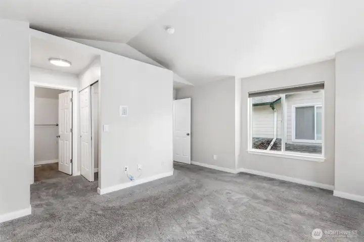 Another view of the primary bedroom with its vaulted ceilings and entry into the private full bathroom.