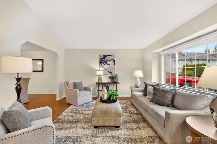 The living room feels open and airy with vaulted ceilings and a wide front window that brings in beautiful natural light. The generous footprint makes it easy to create distinct zones for relaxing, conversation, or a reading corner.