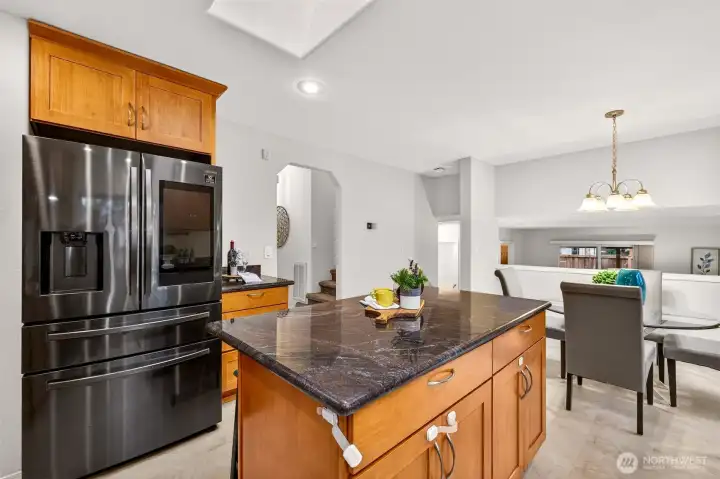 The kitchen centers around a generous island with stone counters, creating an easy hub for prep, serving, and casual meals. Stainless appliances and abundant cabinetry keep everything organized, while the open connection to the adjacent dining area supports effortless entertaining.