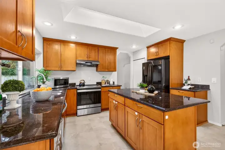Warm cabinetry, stone counters, and stainless appliances give the kitchen a timeless, functional look. The layout provides generous prep zones, excellent storage, and easy flow to the surrounding living spaces.