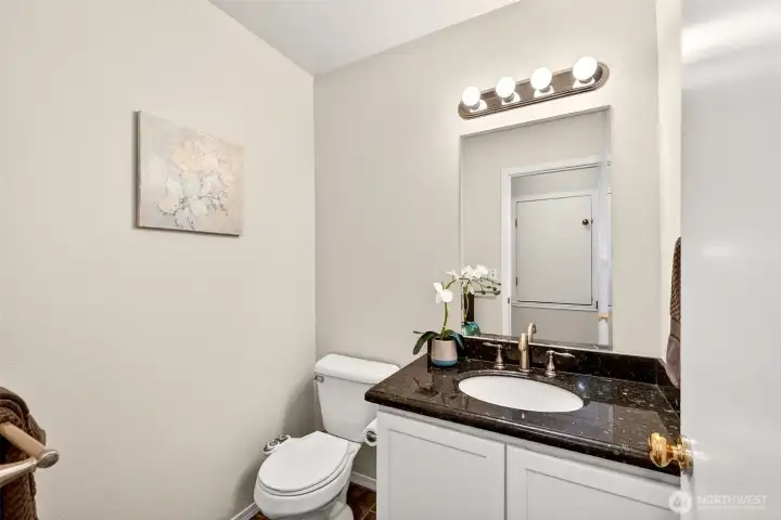 The main floor powder room is conveniently located for guests and everyday use. A stone vanity top and updated lighting add a clean, polished finish.