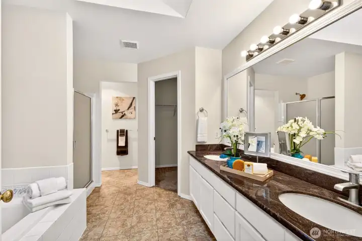 The primary bath is designed for easy mornings with a long dual sink vanity, ample counter space, and a wide mirror with bright lighting. The layout also includes a dedicated bathing area and a walk in closet close by for an efficient daily routine.
