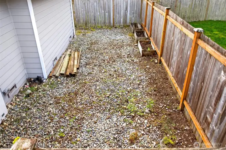 A gravel side area offers extra utility space that’s ideal for storage, projects, or keeping outdoor gear neatly tucked away. Fencing provides clear separation and helps the yard feel defined and private.