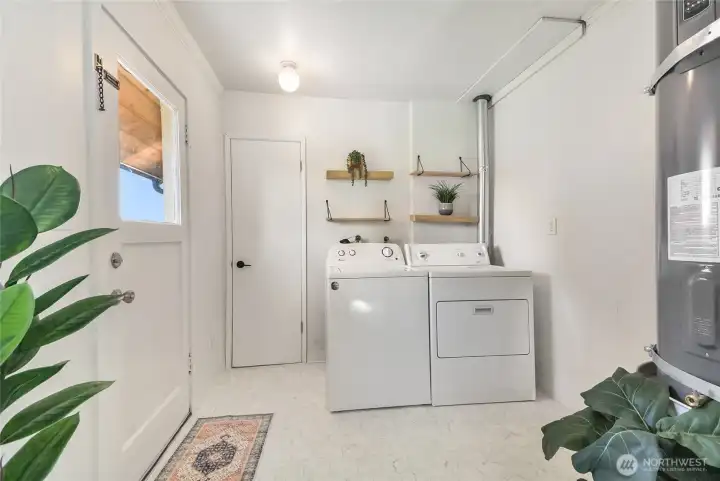 Utility room with door to backyard and door to 3/4 primary bathroom.