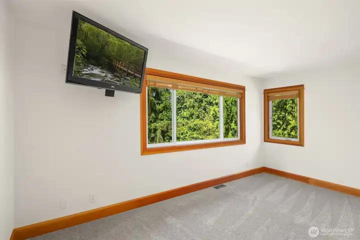 Primary suite with fresh carpet, mounted TV, and picture window overlooking your park like back yard.