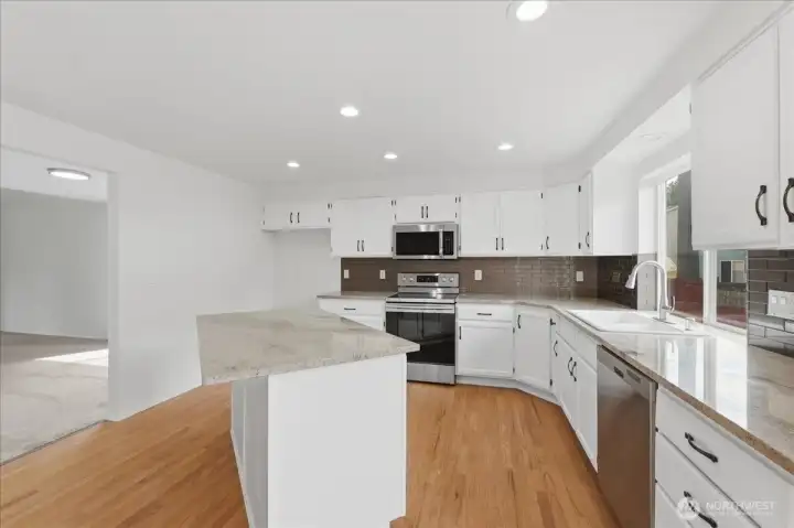 Kitchen with sparkeling counter tops and newer backsplash.