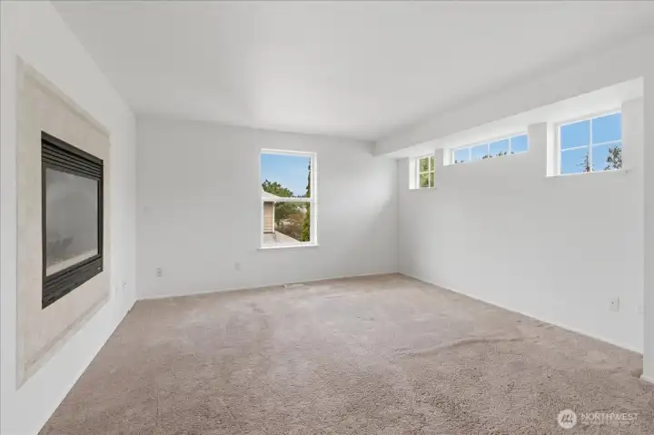 Primary bedroom with natural light and see through gas fireplace.