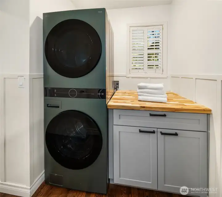Laundry room with newer front-loading washer/dryer and butcher block folding space