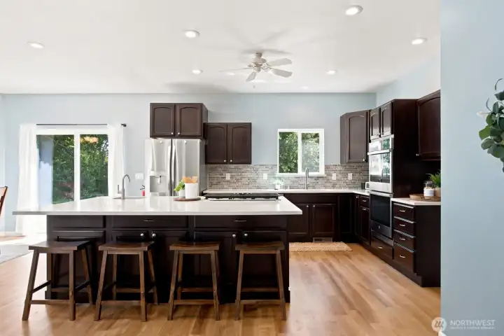 Spacious kitchen featuring a newer stainless steele fridge, oversized island, quartz countertops, and double ovens Spacious kitchen featuring a newer stainless steele fridge, oversized island, quartz countertops, and double ovens