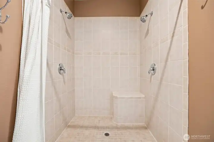 Oversized walk-in shower with dual showerheads, bench seating, and private water closet Oversized walk-in shower with dual showerheads, bench seating, and private water closet